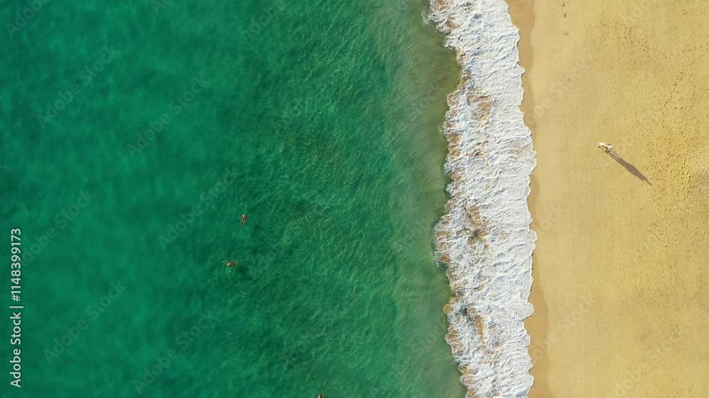 Tropical beach aerial view, Top view of waves break on tropical yellow sand beach. Sea waves seamless loop on the beautiful sand beach. Beautiful tropical beach aerial, bird's eye view of ocean waves.