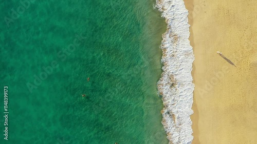 Tropical beach aerial view, Top view of waves break on tropical yellow sand beach. Sea waves seamless loop on the beautiful sand beach. Beautiful tropical beach aerial, bird's eye view of ocean waves.
