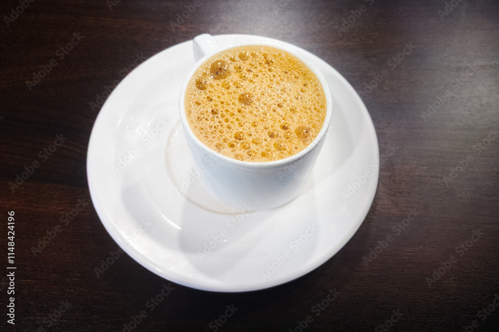 Hot tea in a white cup with a saucer on a wooden table. Hot tea in a white cup with a saucer on a wooden table.