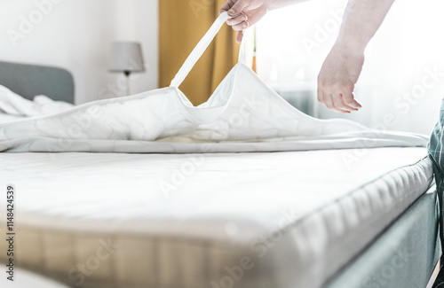 Man changes a new clean mattress topper on a bed. Home duties concept. photo