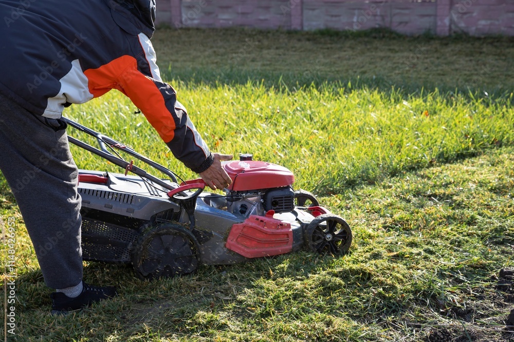 Man Mowing Grass with a Gasoline Lawn Mower in a Backyard Man Mowing Grass with a Gasoline Lawn Mower in a Backyard