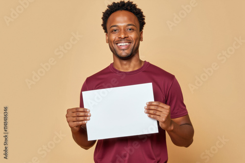 An advertisement studio template portrait photo of a person: an African American man with a bright smile on his face, holding a blank white paper in his hands against a beige background. photo