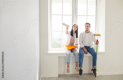 Bilde på lerret Positive and happy family couple dreaming together while renovating and painting new home