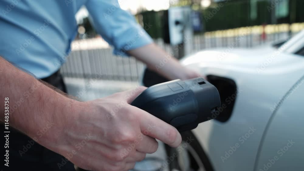 Progressive businessman install charger plug from charging station to his electric car before driving around city center. Eco friendly rechargeable car powered by sustainable and clean energy. Progressive businessman install charger plug from charging station to his electric car before driving around city center. Eco friendly rechargeable car powered by sustainable and clean energy.
