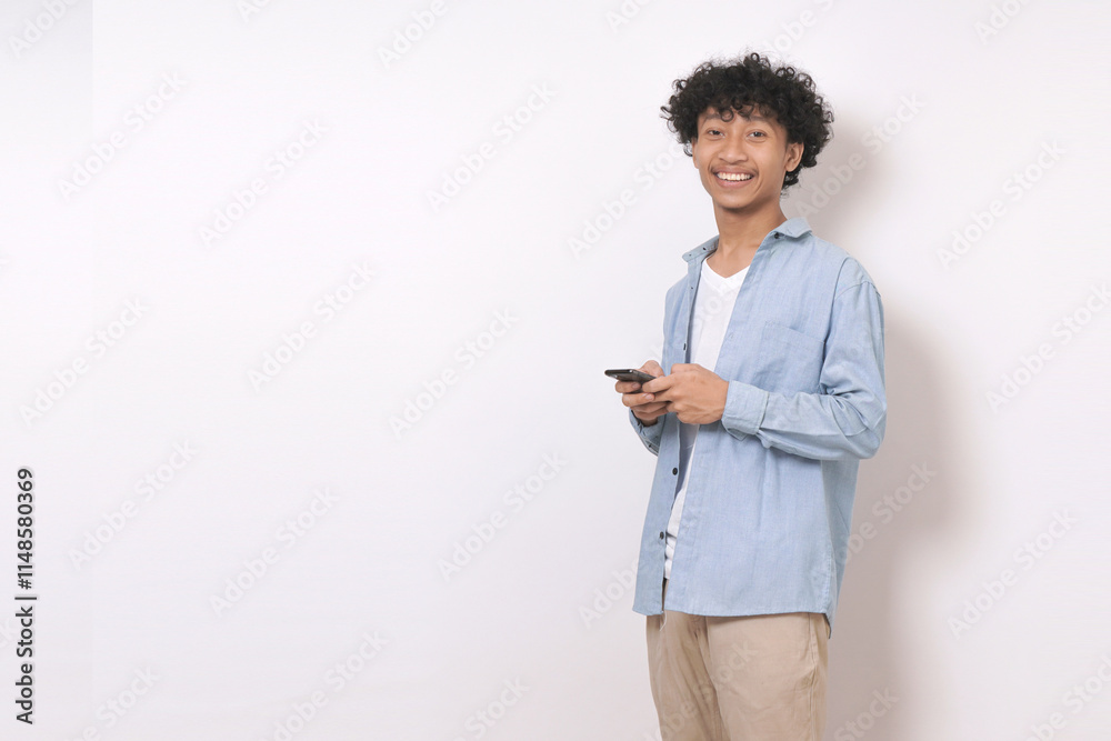 young man standing, holding phone and looking at camera with smile isolated on white background.