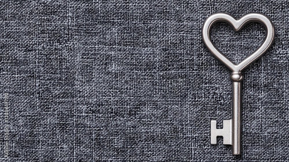 Fototapeta premium Vintage Heart-Shaped Key on Dark Textile Background for Creative Projects