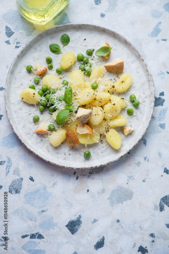 Italian gnocchi with cheese and green peas, vertical shot on a white and blue granite background with space, high angle view Italian gnocchi with cheese and green peas, vertical shot on a white and blue granite background with space, high angle view