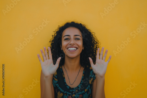 Spanierin vor einer gelben Wand zeigt lächelnd ihre Hände photo