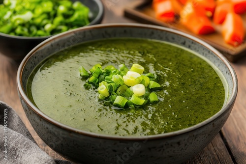 Seaweed is a nutritious superfood. Green soup garnished with chopped scallions in a bowl. photo