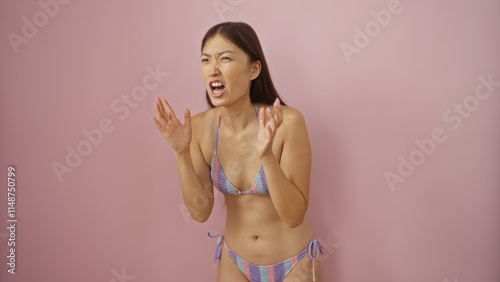 Young chinese woman looking angry in bikini over isolated pink background