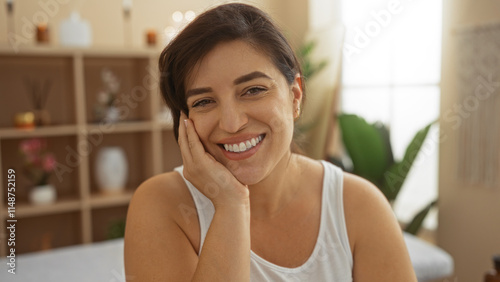 Free Download Woman smiling indoors at a wellness center with a relaxed expression, surrounded by spa decor and tropical plants, showcasing her natural beauty and happiness. - GFXLoad