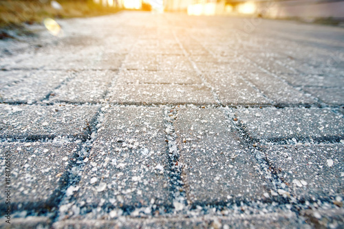 Salt crystals on sidewalk during winter conditions. Excessive winter salt spreading on sidewalks for de-icing, highlighting harmful environmental impact, health risks, and long-term pavement damage.