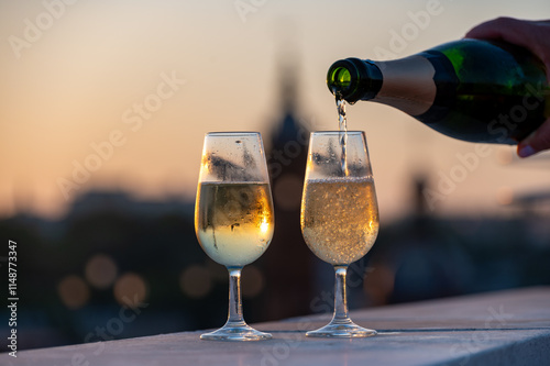 Drinking of cava or champagne sparkling wine on outdoor roof terrace with view on central part of old Sevilla, Andalusia, Spain sunset photo