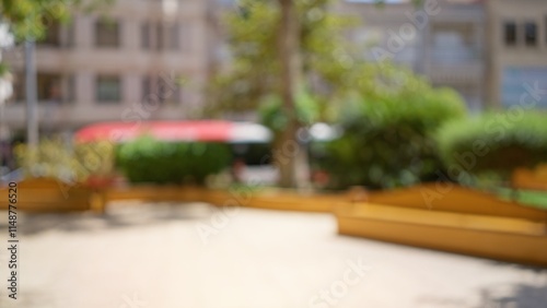 Outdoor blurred background in a sunny park with trees and benches under bright daylight creating a bokeh effect