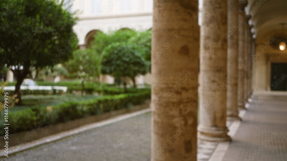 Fototapeta premium Blurred stone columns and lush greenery at an old university campus create a peaceful, defocused outdoor scene with historical charm.