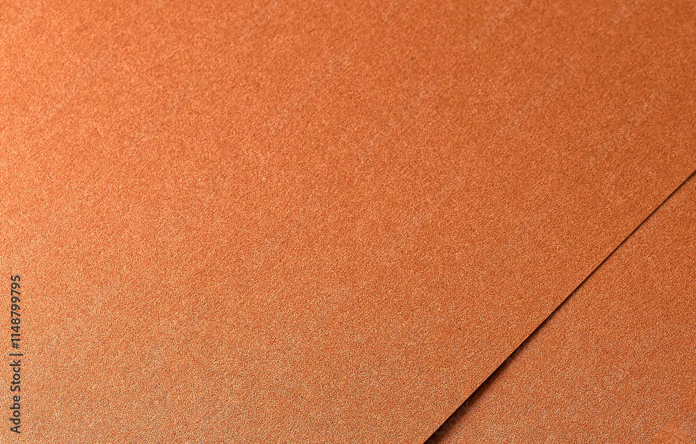 Fototapeta premium Copper paper texture with a metallic, glossy finish in warm tones of orange, brown, and terracotta. The grainy, layered surface with subtle shine and shimmer creates a rich,