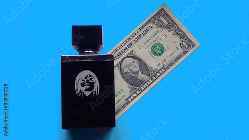 Perfume bottle with dollar bill on blue background. Top view shot, fragrance and dollar bill