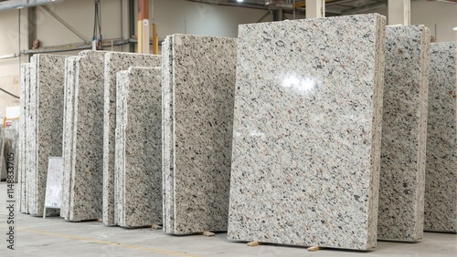 High stack of granite slabs in stone processing facility with soft natural light and concrete floor