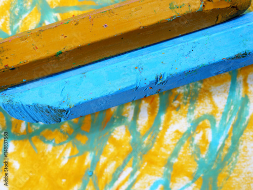 used and broken colored crayons on painted paper background
