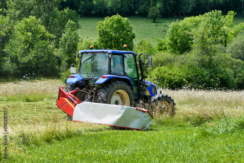Tractor cutting grass in a field prior to drying and baling
 photo