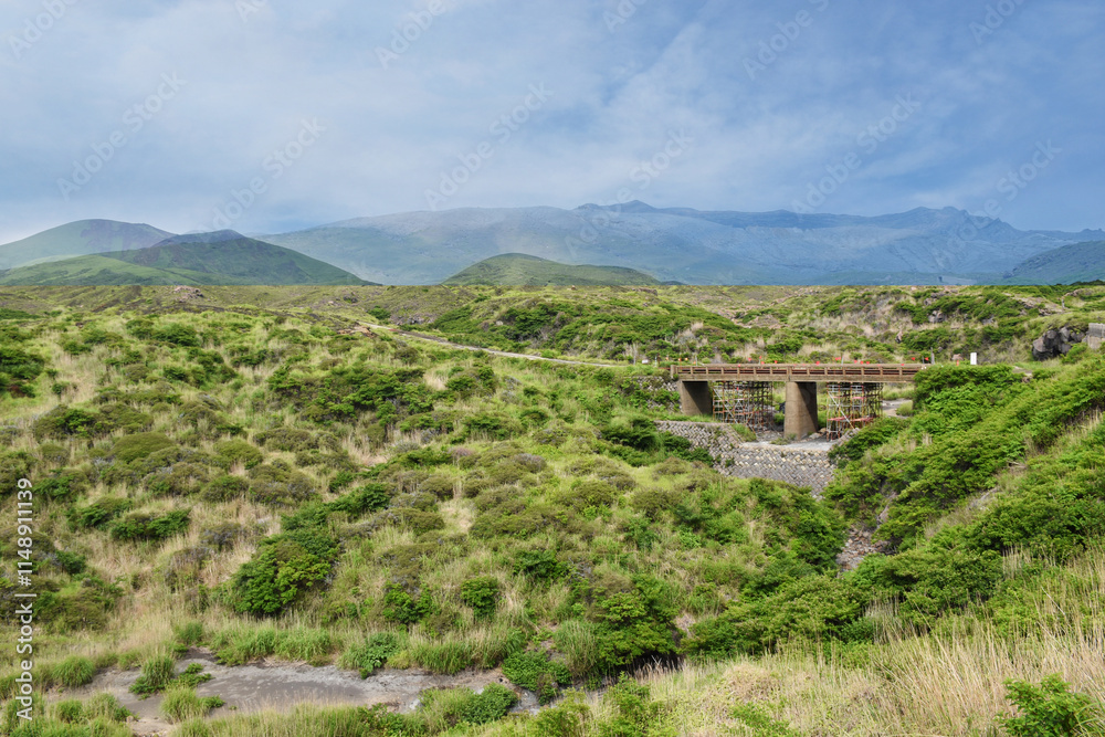 A collapsed road bridge surrounded by dense green vegetation (Sugaru Kuzure), Japan. Broken metal beams and debris are visible at the bottom of the steep ravine. A collapsed road bridge surrounded by dense green vegetation (Sugaru Kuzure), Japan. Broken metal beams and debris are visible at the bottom of the steep ravine.