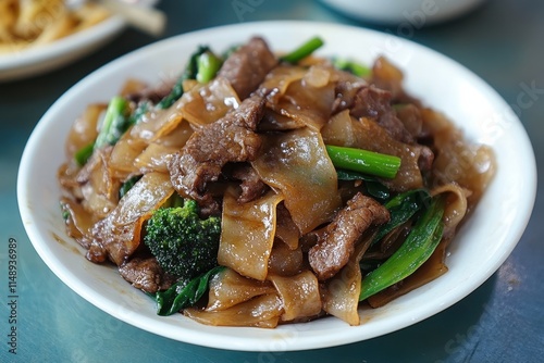 Pad see ew is a popular Thai street food featuring stir fried flat rice noodles beef and Chinese broccoli flavored with dark soy sauce photo