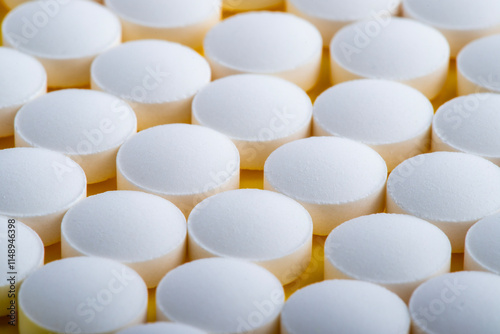 White round pills isolated on a yellow background. A heap of small round meds. Health care and medicine concept