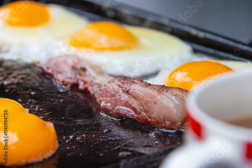 Cooked breakfast on a barbeque hot plate closeup with eggs and bacon