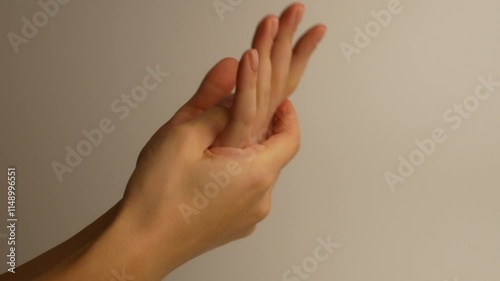 The girl moisturizes her hands by rubbing the cream on her palms.