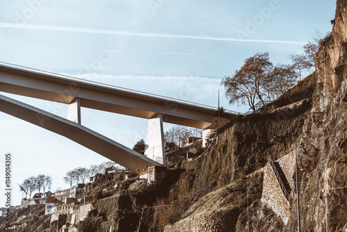 Photography Ponte do Infante Bridge spans a rocky hillside with terraced walls and scattered