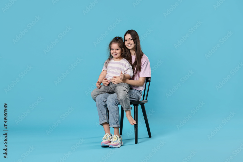 Portrait of cute sisters on light blue background Portrait of cute sisters on light blue background