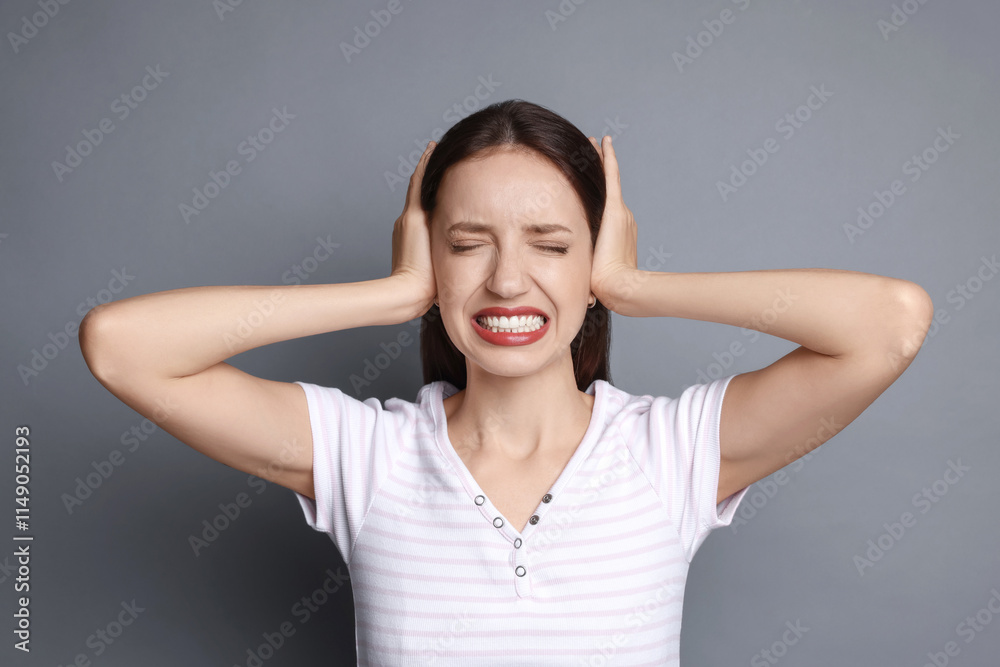 Woman covering her ears on grey background Woman covering her ears on grey background