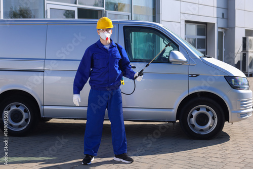 Pest control worker with spray tank outdoors photo