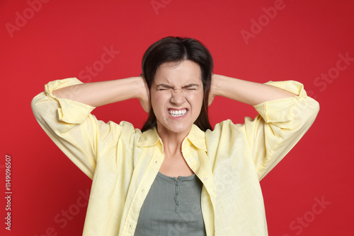 Woman covering her ears on red background photo