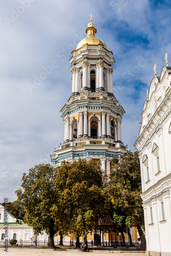 A tall, gold and white tower with a gold dome sits in front of a white building