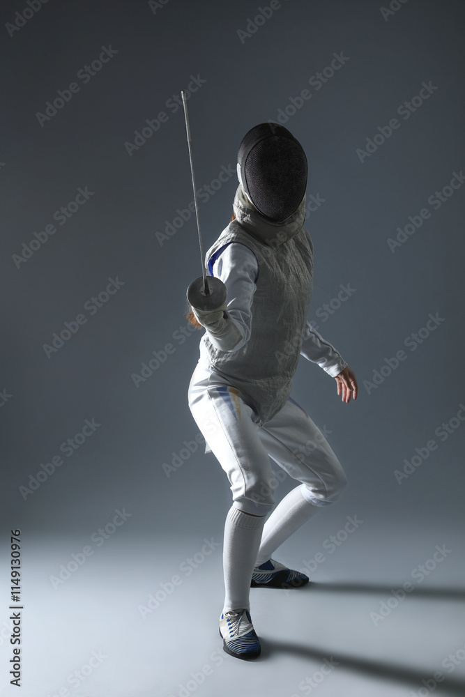 Fencer with epee practicing on gray background Fencer with epee practicing on gray background