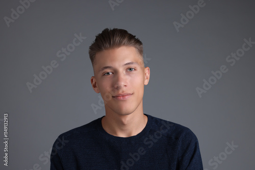 Handsome young man with stylish haircut on grey background