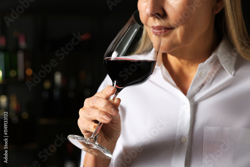 Professional sommelier tasting red wine indoors, closeup