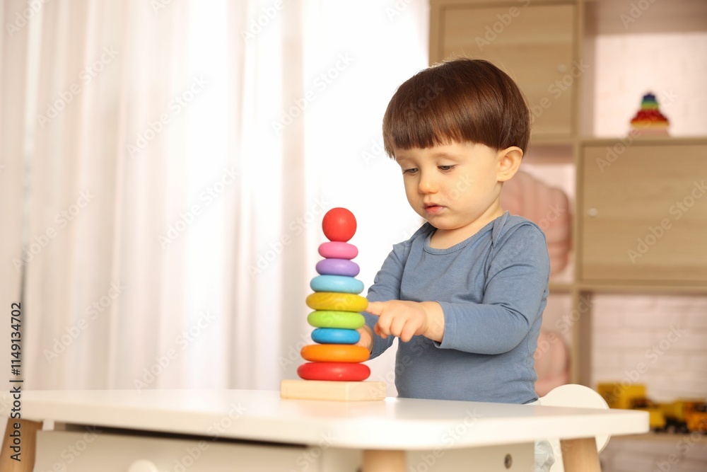 Cute little boy playing with toy pyramid at table indoors, space for text Cute little boy playing with toy pyramid at table indoors, space for text