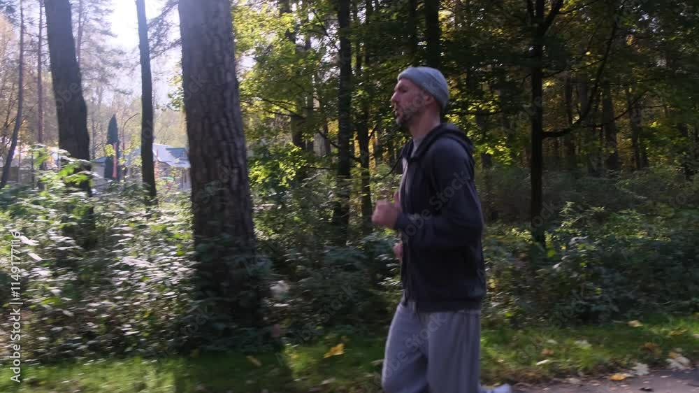 Man running through a fall forest in activewear. Trees surround the path with yellow and green foliage