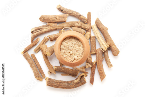 A mud pot filled with organic Liquorice or Mulethi (Glycyrrhiza glabra) powder, placed on a heap of liquorice roots, isolated on a white background.