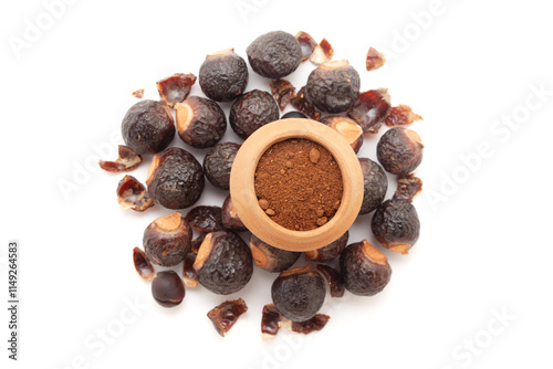 A mud pot filled with organic Soapnuts or Reetha (Sapindus mukorossi) powder, placed on a heap of Soapnuts berries, isolated on a white background. photo