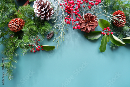 Winter green leaves and berries composition on green background. Winter and Christmas decoration background. Natural elements design for Merry Christmas and Holiday.