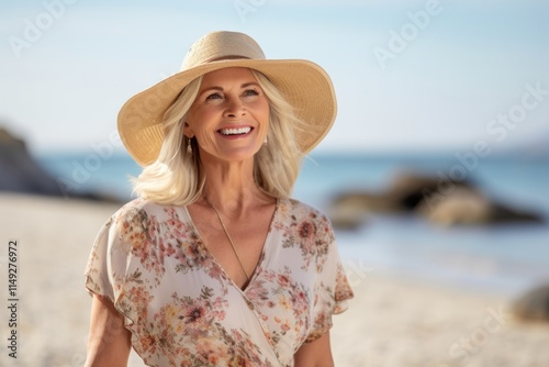 Beautiful mature woman in summer dress and hat on the beach.