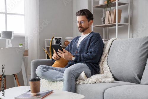 Young man with e-reader sit...