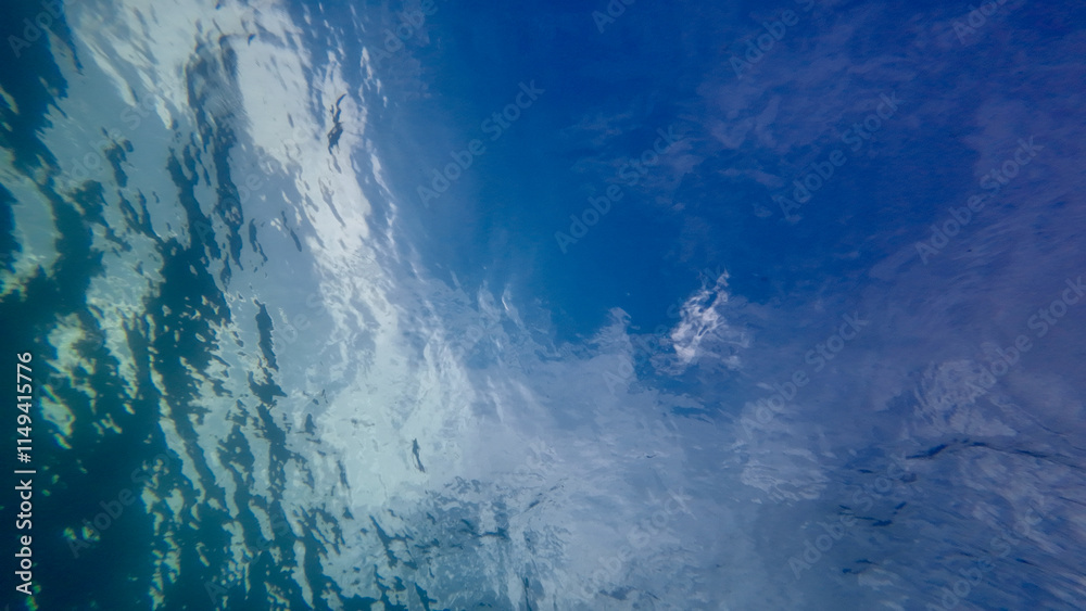 Obraz premium View from underwater to the sea surface. View from the bottom of the sea to the sky with clouds through the clear transparent thickness of water.