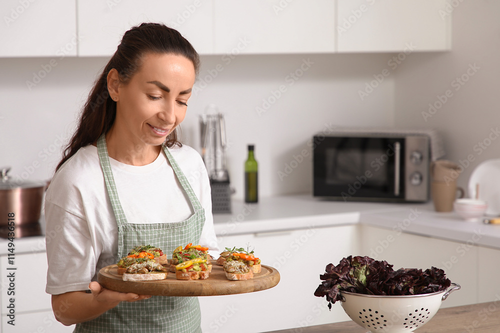 Beautiful woman holding board with tasty vegan bruschettas in kitchen Beautiful woman holding board with tasty vegan bruschettas in kitchen
