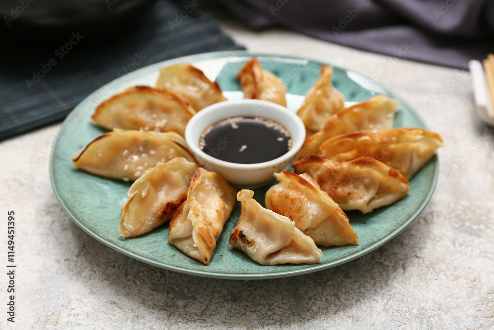 Plate with fried Japanese gyoza and bowl of soy sauce on white background, closeup Plate with fried Japanese gyoza and bowl of soy sauce on white background, closeup