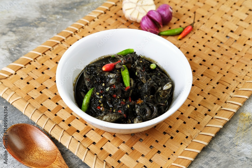 A delicious bowl of stir-fried squid in rich black ink sauce or tumis cumi hitam, garnished with fresh red and green chilies. This traditional seafood dish is beautifully presented, A delicious bowl of stir-fried squid in rich black ink sauce or tumis cumi hitam, garnished with fresh red and green chilies. This traditional seafood dish is beautifully presented,