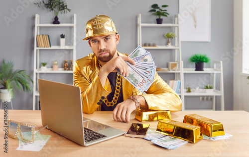 Portrait of a serious rich man in a gold suit holds cash money while working on a laptop. Wealth, prosperity, and financial success, highlighting his dedication and serious approach to his work.